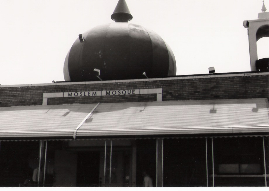 Black and white closeup of the AMS dome with the words 'Moslem Mosque' visible on the brick facade below the dome