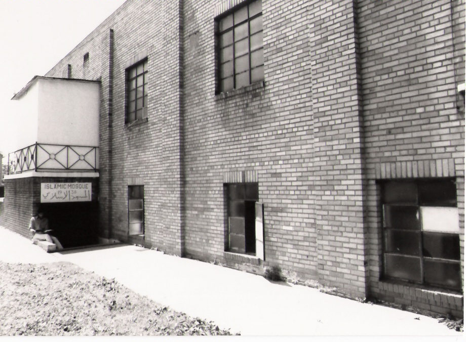Black and white photo of the side of the original AMS building with a sign reading 'Islamic Mosque 1938'